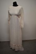 A 1960s white long sleeved gown, having floral pink and white lace overlay and pink ribbon to