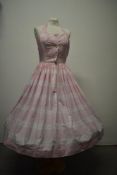 A 1950s pink cotton halter neck day dress having white abstract design, full skirt, button down