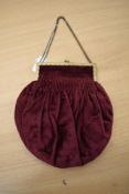 An early 20th century burgundy velvet smocked evening bag, having gold tone frame, chain strap and