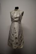 A 1960s cream dress, having floral padded appliqué raised decoration, high neckline with bow to