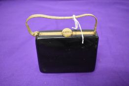 A 1950s bag/compact, having various compartments to hold a comb, writing paper, face powder and