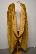 A vintage opera cape, around 1930s, of mustard yellow velvet with motif pattern and lined in peach