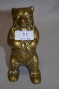 An antique brass money box in the form of a bear.