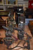 A variety of vintage lamps and blow torches, including storm lamps, brass lamp bases and carriage