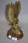 A mid century brass eagle study mounted on turned wooden base.