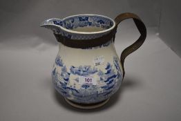 An antique blue and white jug having traditional oriental style transfer pattern, having metal