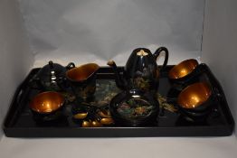 A Chinese lacquered coffee set, comprising tray cups, saucers, spoons, jug etc, having black