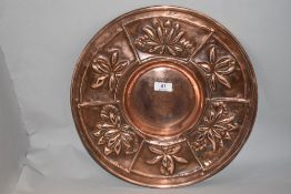 A copper charger of Arts and Crafts design, having embossed flowers to border.