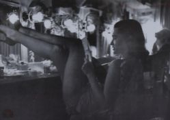 A reproduction monochrome photographic print, a 1950's showgirl relaxing between performances,