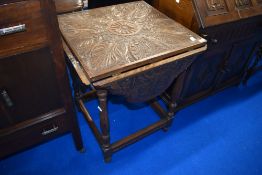 A 19th Century oak occasional table having carved top and four drop flaps