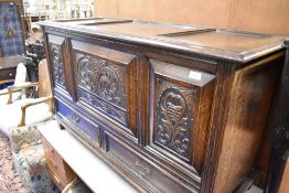 A late 19th or early 20th Century oak kist having carved panels and drawers to base