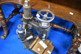 A vintage drill or similar stand with microscope attachment