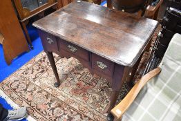 A Georgian oak lowboy having three drawers , brass drop handles and shaped apron