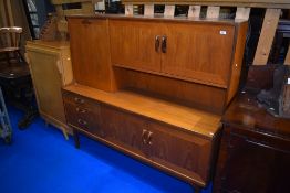 A vintage teak sideboard with drop flap and cupboards to top , with triple drawer and double