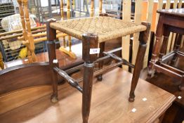 A traditional stained frame stool with strung seat