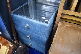 A vintage upholstered bedside chest of three drawers