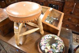 A traditional three legged stool with leather top and golden oak frame, along with a modern tapestry
