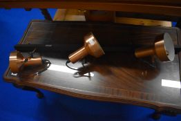 A vintage lighting track with three copper effect spots