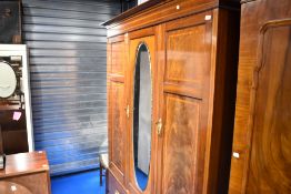 A 19th Century triple wardrobe having central mirror door and drawer base