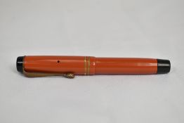 A Parker Streamlined Junior Duofold button fill fountain pen in coral red with two rings to the
