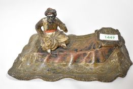 A cast metal Indian ink well depicting smoking man on flying carpet