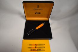 A boxed Delta Dolcevita rollerball pen in orange maarble and black and silver trim. As new condition