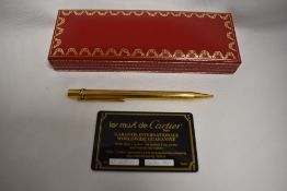 A Cartier Must de Cartier ballpoint pen in a gold metal with tri-colour banding on lid, with
