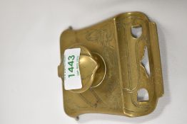 A small brass inkwell pen rest
