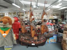A wooden model of a Galleon having extensive rigging decoration, sails damaged, on wood stand,