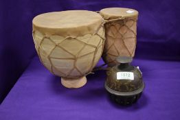An Indian style tabla drum in terracotta an animal hide with an Indian brass bell.