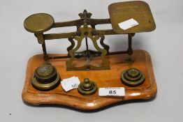 A set of vintage brass postal scales with weights, sat on wood base.