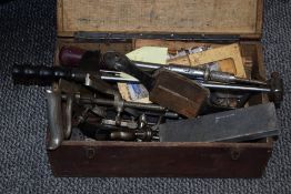 A wooden box containing an assortment of tools, including torque wrench, hand planes, sharpening