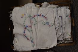 A box full of vintage table linen, including embroidered examples.