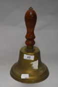 A vintage brass hand bell with wooden handle.