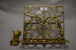 A vintage brass adjustable book rest and a Victorian pressed tin and brass paper clip in the form of
