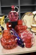 A collection of vintage cranberry glass wares including water jugs, vases and bowls.