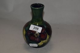 A mid century Moorcroft vase, having tube lined anemone pattern on green and teal ground.