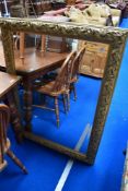 A gilt frame over mantel mirror of large proportions with vine decoration