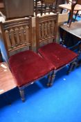 A pair of Victorian oak dining chairs having spindle backs and over stuffed seats