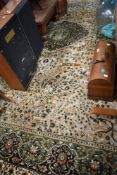 A large room sized carpet square , in shades of cream, black and green
