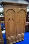 A stripped pine wardrobe in the Victorian style having drawer base