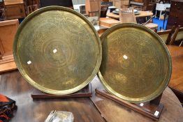 Two eastern brass trays of circular form with stained frame stands