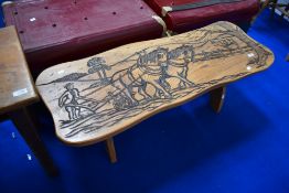 A traditional golden oak coffee table having carved ploughing decoration, width approx. 111cm