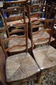 Two pairs of rush seated kitchen chairs having shaped ladder backs
