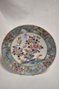 A Chinese enamelled porcelain plate, decorated with flora and fauna within a diaper and foliate