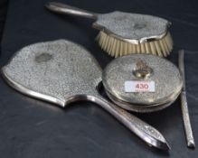 A white metal and white metal mounted four-piece dressing table set, comprising a hand mirror,