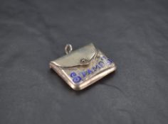 A George V silver an enamel stamp case, formed as a clutch bag with hinged cover and worded 'stamps'