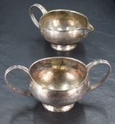 A Queen Elizabeth II silver sugar and cream, of circular form with moulded strap handles, short