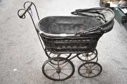 A vintage dolls pram of wood and metal.