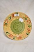A glazed earthenware plate, the border decorated with repeating floral motifs, and having a green